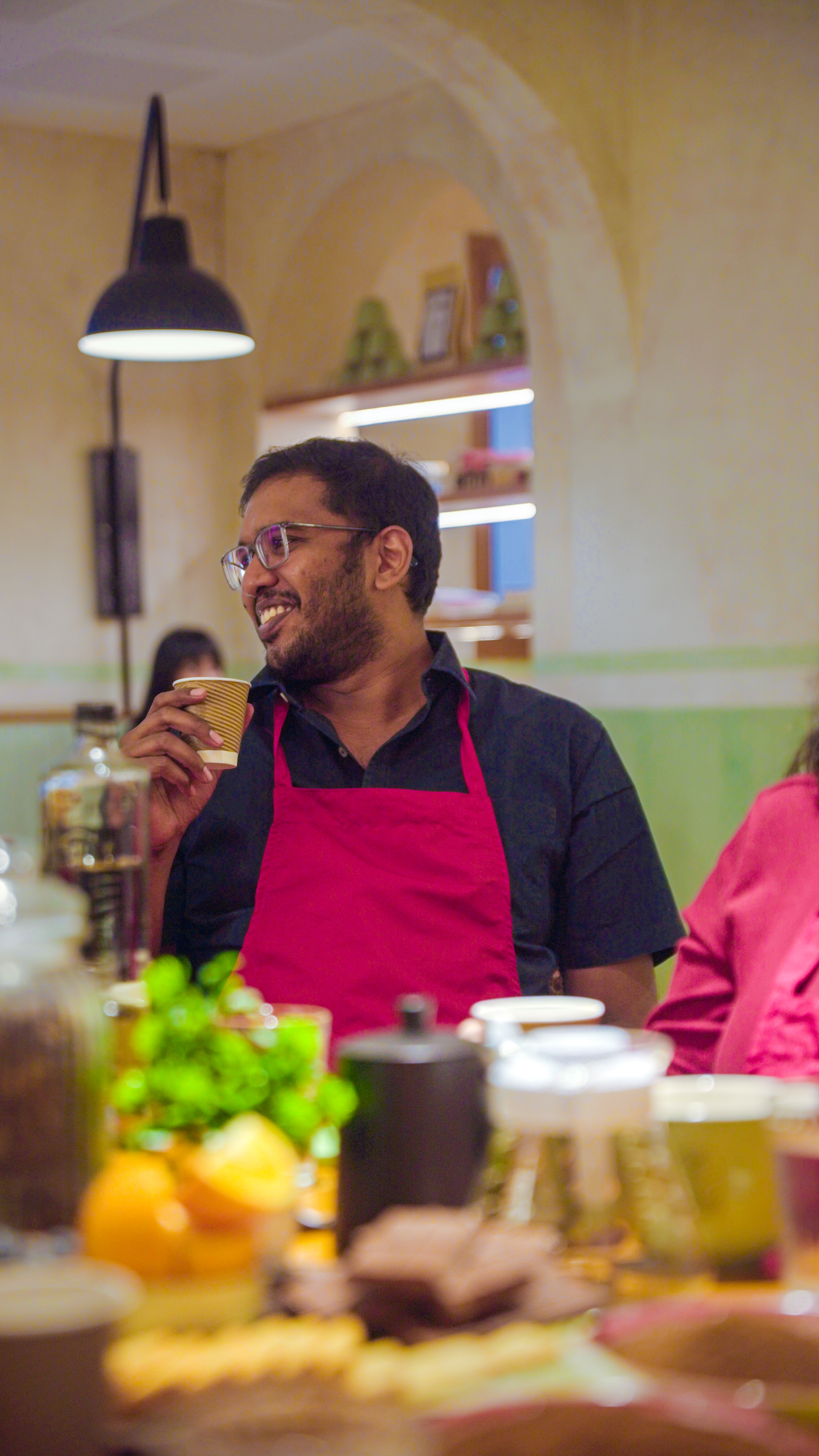 Smiling male participant wearing a red apron during the coffee brewing workshop.